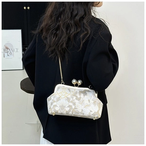 Détail du sac brodé vintage avec fermoir à perles double et bandoulière en chaîne dorée