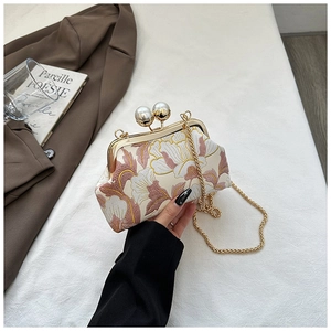 Détail de broderie florale sur sac de soirée vintage avec fermoir perle et chaîne dorée