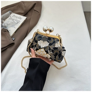 Détail de broderie florale vintage sur tissu noir avec élégant fermoir à double perles