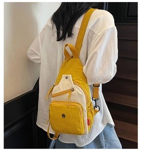Détail du sac bandoulière en nylon jaune et beige avec poches zippées et sangle