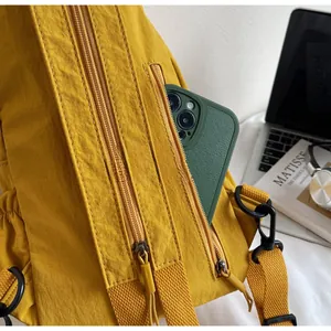 Détail du sac à bandoulière en nylon jaune avec poches zippées et crochet pivotant noir