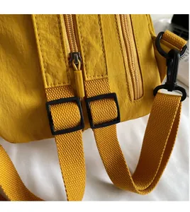 Détail macro du tissu en nylon, zip métallique et bandoulière réglable du sac jaune