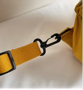 Détail d'un crochet rotatif noir et d'une sangle jaune sur un sac à dos en nylon