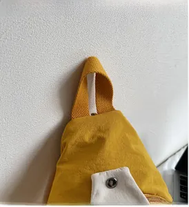 Détail d'un sac jaune en tissu plissé avec poignée tressée et bouton pression en métal