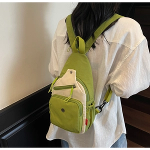 Détail d'un sac à dos en nylon vert et crème avec plusieurs poches porté sur le dos