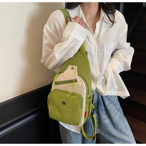 Détail du sac à bandoulière vert et beige avec fermetures éclair et sangle réglable