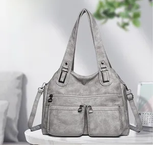 Détail du sac fourre-tout gris texture litchi avec deux poches avant zippées et métal