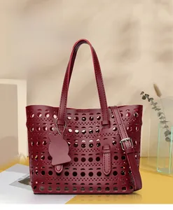 Detail of dark red hollow-out tote bag with cat charm and adjustable shoulder strap