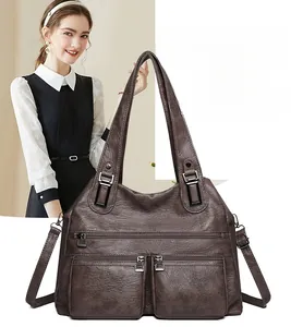 Détail du grand sac bandoulière marron montrant les multiples poches et la texture cuir