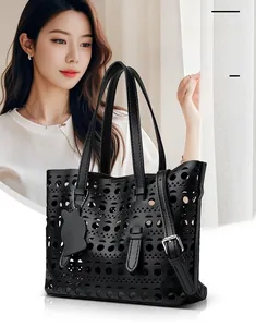 Detail view of black laser-cut geometric patterns and a cat-shaped charm on the tote bag