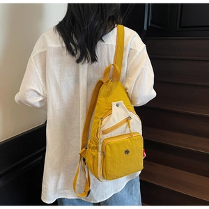 Détail d'un sac à bandoulière jaune plissé avec poches zippées porté sur le dos