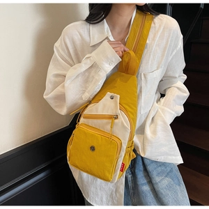 Détail du sac bandoulière jaune et blanc montrant les compartiments et le nylon froissé
