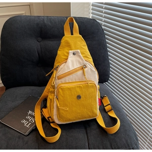 Détail d'un sac de poitrine en toile moutarde et beige bicolore sur un canapé