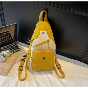 Détail du sac bandoulière en toile jaune avec plusieurs poches et étiquette de marque rouge