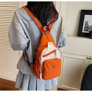 Détail du sac en nylon orange et blanc cassé avec plusieurs compartiments zippés pratiques