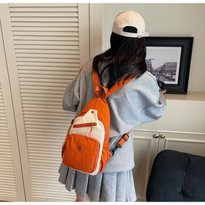 Vue détaillée du sac bandoulière plissé orange et blanc cassé porté avec style