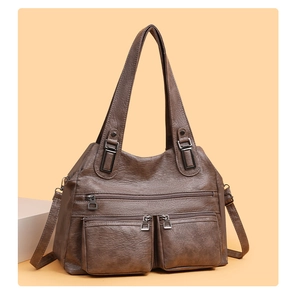 Détail d'un sac en cuir marron foncé avec plusieurs poches zippées et métal vintage