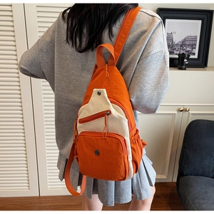 Vue détaillée du sac bandoulière en nylon orange et beige avec sangle réglable et poches