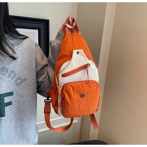 Détail du sac bandoulière en nylon orange et blanc avec boucle en métal et zips pratiques