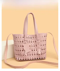 Detail of laser-cut geometric patterns on a soft pink handbag with adjustable strap