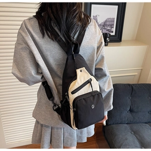 Détails d'un sac bandoulière noir et blanc avec poches zippées et sangle en nylon réglable