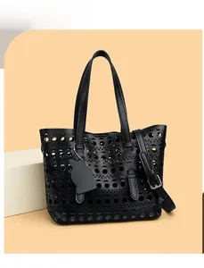 Detail of black laser-cut hollow tote bag with cat charm and adjustable strap