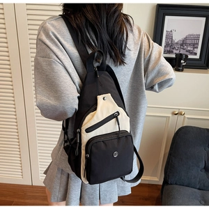 Détail d'un sac bandoulière léger contrasté montrant le nylon texturé et les fermetures