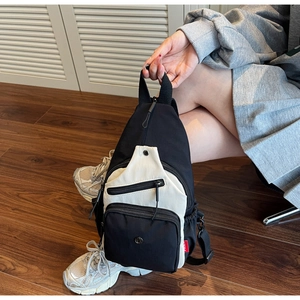Détail d'un sac de poitrine en toile noir et blanc avec logo rond et couches à glissière