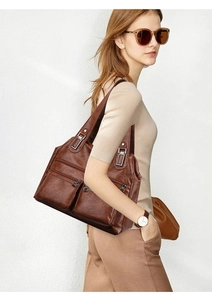Détail d'un sac bandoulière marron foncé vintage avec des poches zippées et boucles métal