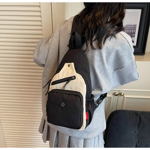 Vue détaillée du dos d'un sac bandoulière en nylon noir et beige porté par une personne