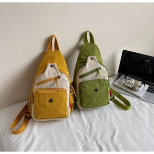 Détail de sacs bandoulière en toile bicolore jaune et vert avec multiples poches