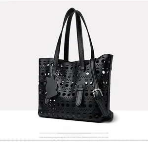 Detail of black laser-cut tote bag with hollow patterns and cat charm accessory