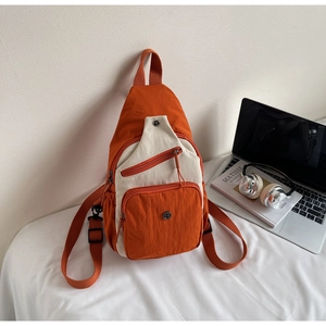 Détail du sac à bandoulière en nylon bicolore orange et crème avec ordinateur et casque
