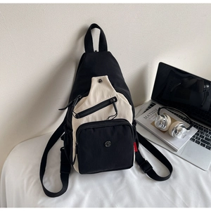 Gros plan d'un sac bandoulière en toile noir et blanc avec plusieurs compartiments zippés