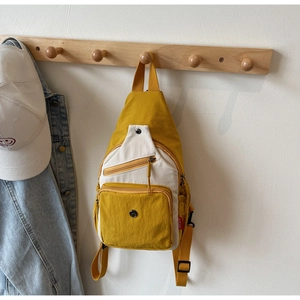 Détail du sac bandoulière en toile jaune avec zips et sangle réglable sur crochet en bois