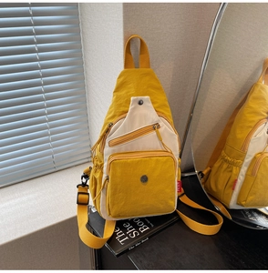 Détail du sac bandoulière en toile jaune contrastée avec poches zippées multiples