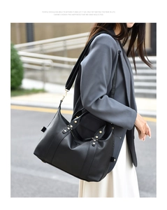 Borsa Boston nera in pelle a grana con rivetti indossata da una modella in abiti casual