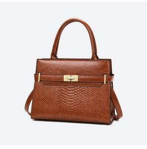 Detailed view of the brown embossed crocodile texture and gold hardware buckle on the handbag