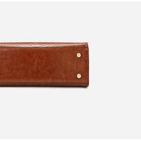 Detail of vintage brown leather bag bottom with embossed texture and gold protective studs