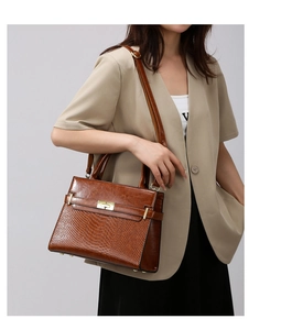 Detail of vintage brown embossed tote with golden clasp and adjustable strap on a model