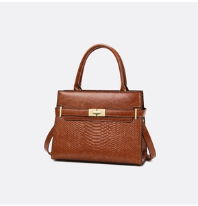 Close-up of structured brown bag with smooth leather and crocodile texture panels