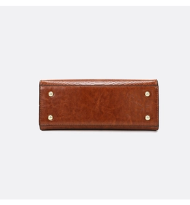 Detail of brown handbag bottom with gold studs and embossed snake pattern texture
