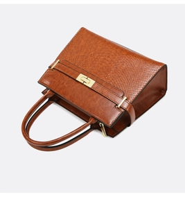 Detail of vintage brown leather handbag featuring snakeskin pattern flap and gold hardware