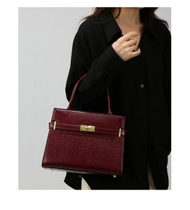 Detail of burgundy vintage handbag showing textured snake skin pattern and gold twist lock
