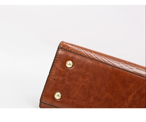 Detail of vintage brown leather bag base with gold metal feet and refined stitching