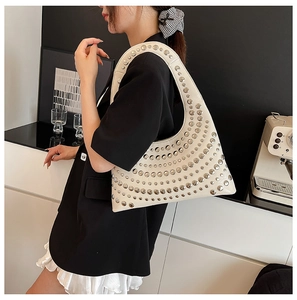 Detail der cremefarbenen Hobo-Tasche mit silbernen Nieten in Lifestyle-Umgebung