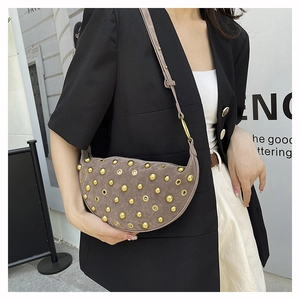 Close-up of brown suede moon bag with golden studs and metal eyelets on model