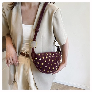 Détails du sac demi-lune en daim bordeaux avec rivets dorés et œillets vintage