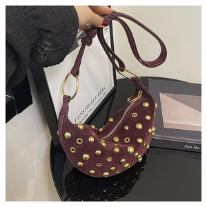 Détail du sac croissant en daim bordeaux avec rivets dorés et poignées à anneaux