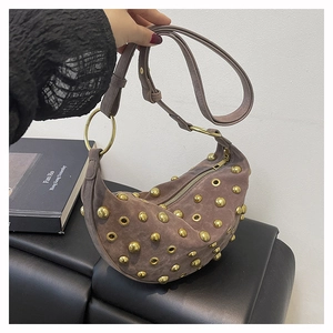 Détail d'un sac demi-lune en daim marron avec rivets dorés et bandoulière réglable